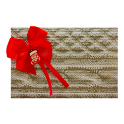 Pakowanie na prezent w papier ze wzorem sweterkowym, czerwoną kokardką i ozdobą świąteczną