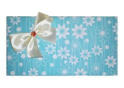 Pakowanie na prezent w błękitny papier w kwiatki z kremową kokardką i czerwonym kwiatkiem