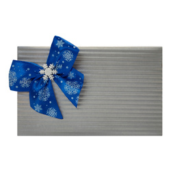 Pakowanie na prezent w srebrny papier z niebieską wstążką w śnieżynki